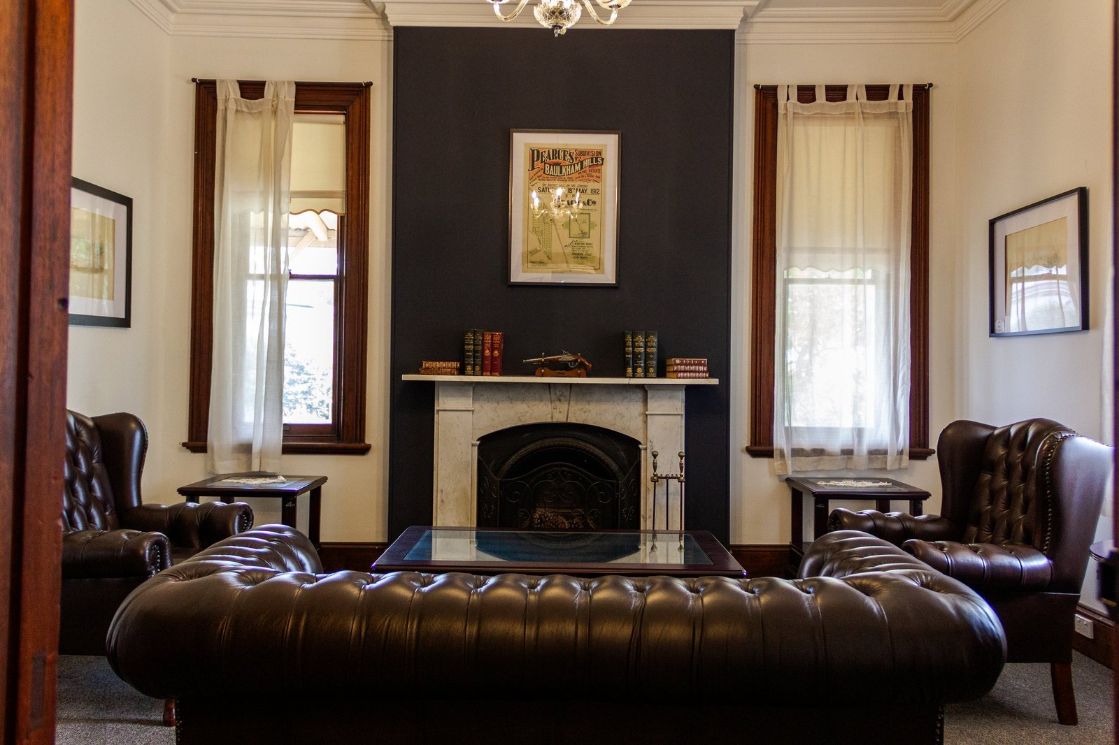A sitting room in the homestead featuring a heritage pump organ, chesterfield sofa and a view through to the library.